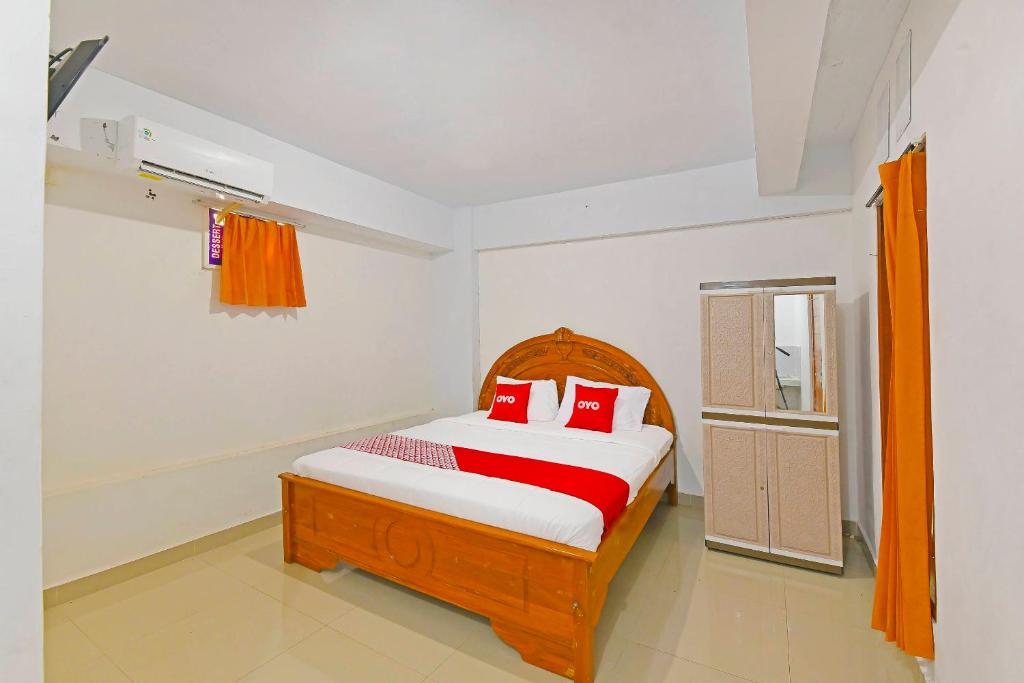 a bedroom with a wooden bed with red pillows at OYO 90967 Soka Asri Guest House in Darmasaba