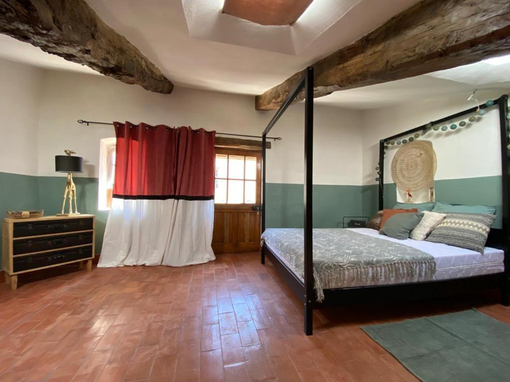 1 dormitorio con cama con dosel y ventana en La Tour des Baronnies à la Porte de l eau, en Saint-Auban-sur-Ouvèze