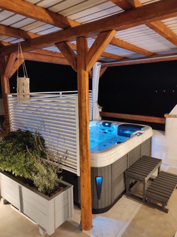 uma banheira de hidromassagem num pátio com uma pérgola de madeira em Kontoudi's House em Áno Sangríon