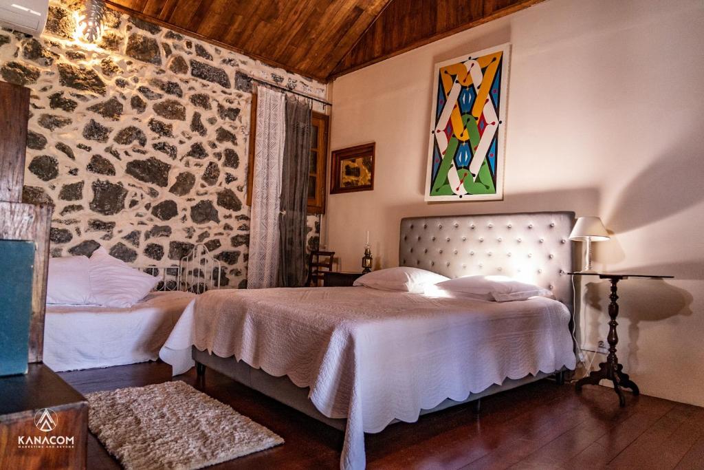 a bedroom with two beds and a stone wall at Les Grands Monts in Saint-Joseph