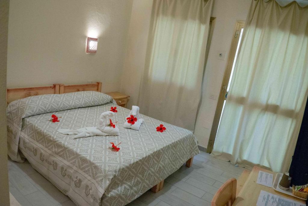a bedroom with a bed with red flowers on it at Hotel L'Oleandro in Villasimius