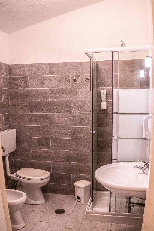 a bathroom with a shower and a toilet and a sink at Hotel L'Oleandro in Villasimius