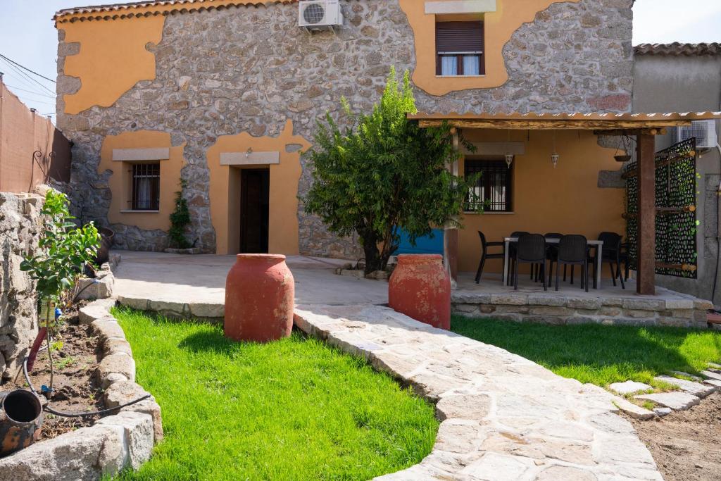een stenen huis met een tafel en stoelen ervoor bij EL PATIO DE LAS TINAJAS in Sotillo de la Adrada