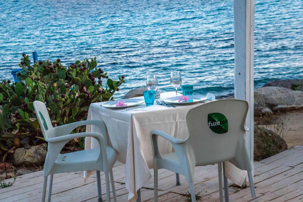 a table with two chairs and a table with wine glasses at Hotel L'Oleandro in Villasimius