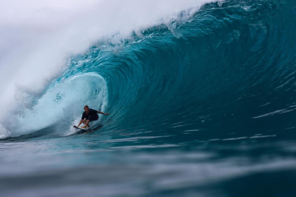 um homem a surfar uma onda numa prancha de surf no oceano em Cabana Surf and Stay em Biha