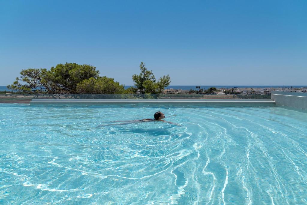 a person swimming in a large swimming pool at Perla Saracena Hotel & Restaurant in Salve