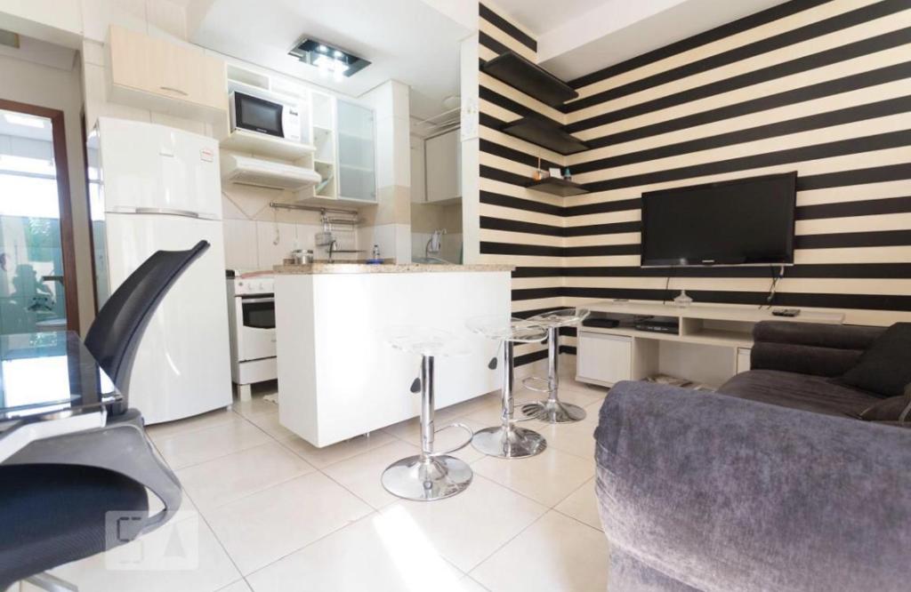 a living room with a couch and a tv on a wall at FlatsRose CH Flamboyant Conforto e qualidade in Goiânia
