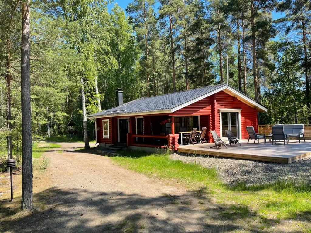 a red cabin in the woods with a wooden deck at Säilöksen Lomahuvilat in Luhanka