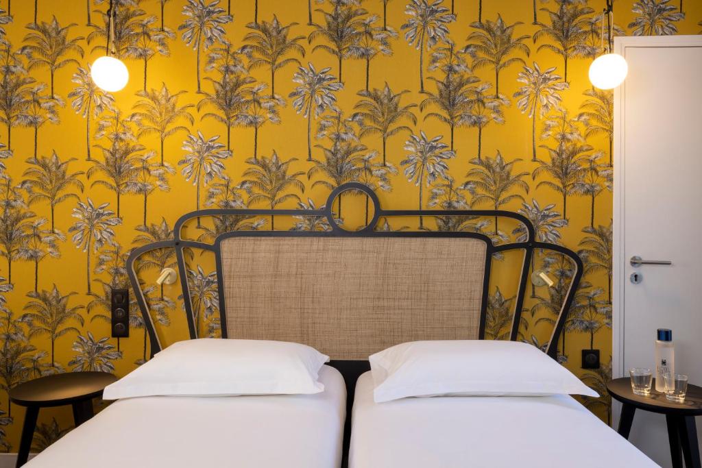 two beds in a room with yellow wallpaper at Hotel De Suez in Paris