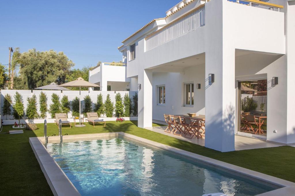 a villa with a swimming pool in front of a house at THE QUAD Luxury Villas in Lygia