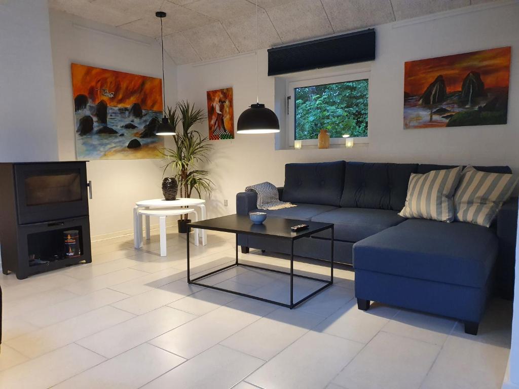 uma sala de estar com um sofá azul e uma televisão em Airbnb-lejligheder, Villerslev 