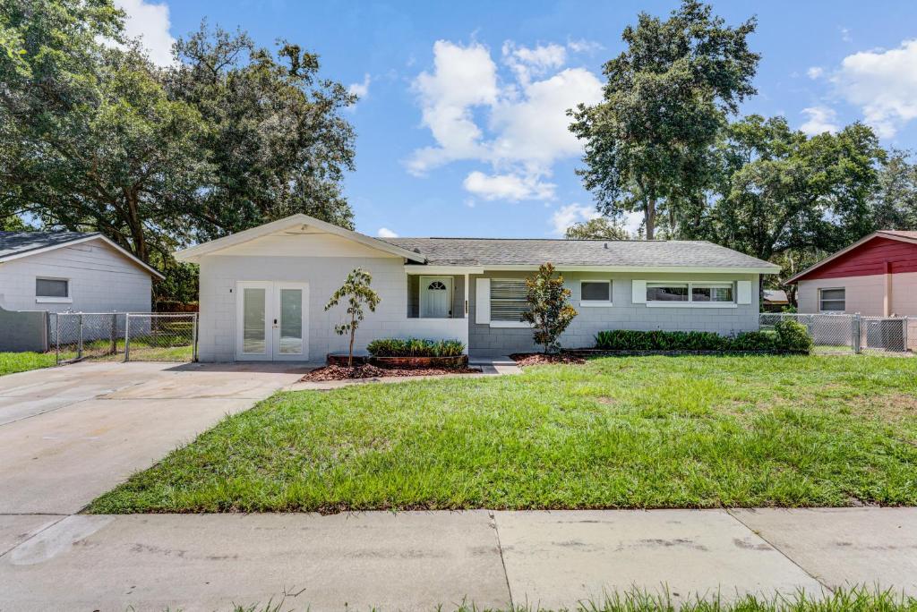 a white house with a yard at Quiet Location Duplex House - Minutes Away from Everything - Winter Park, Florida in Orlando