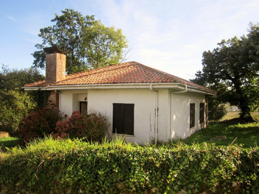 una vieja casa blanca con chimenea en Villa May en Riegu Vidiago Llanes, en Vidiago