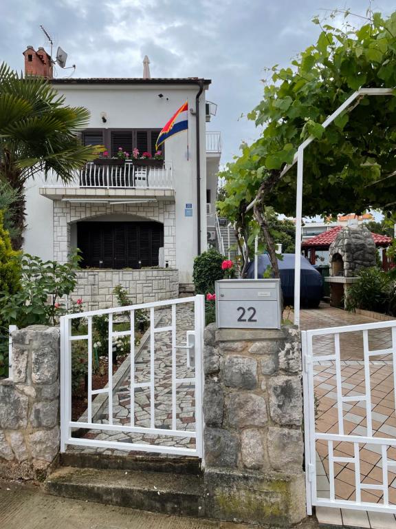 a white gate with a flag in front of a house at Casa Estancia Apartment in Njivice