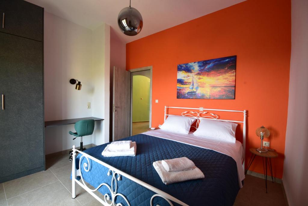 sypialnia z łóżkiem z pomarańczową ścianą w obiekcie Konatsi Luxury Apartments w mieście Tyros