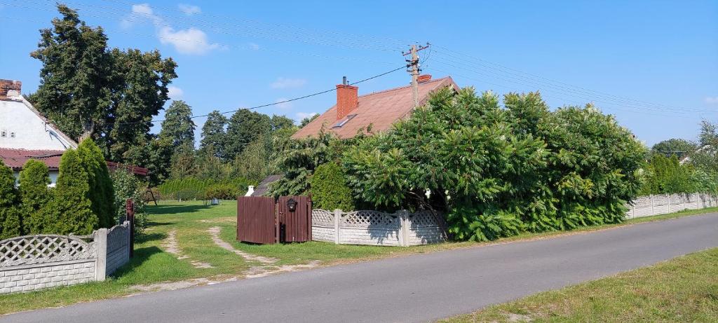 a house with a white fence next to a road at Agroturystyka Zielony Zakątek in Grudna