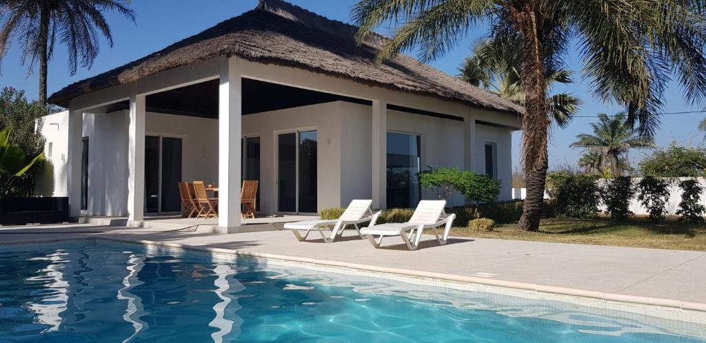a villa with a swimming pool in front of a house at Villa Cap Ouest Piscine Grand Jardin à 2 Pas de l'Océan in Cap Skirring