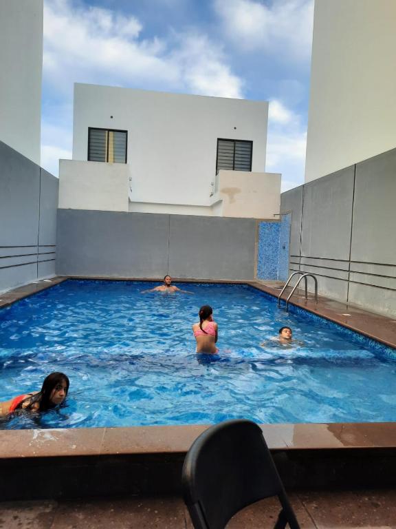 a group of people swimming in a swimming pool at Departamento Moderno Alberca Compartida - 6 Personas in Mazatlán