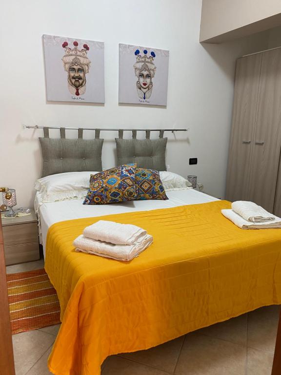 a bedroom with a yellow bed with towels on it at Holiday mode EVA in Partinico