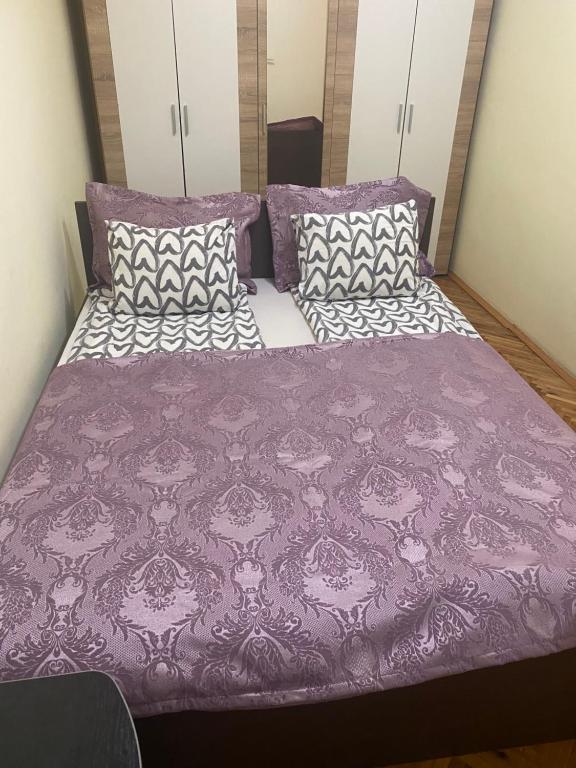 een bed met een paars dekbed en kussens bij Garden apartmani 3 in Vračar (historical)