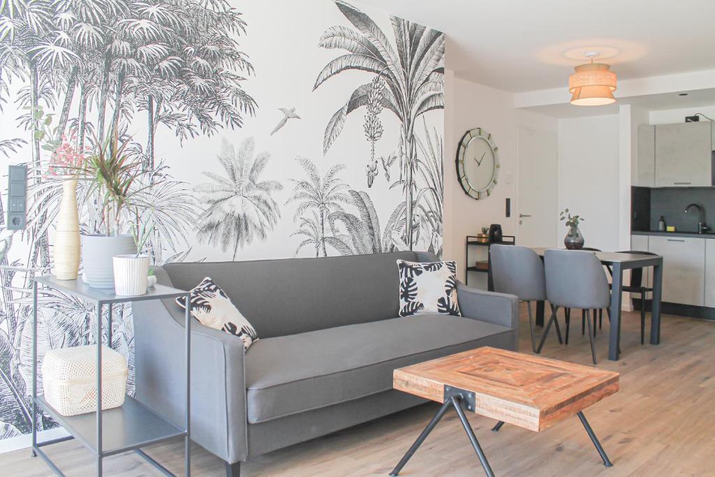 uma sala de estar com um sofá cinzento e um mural de palmeiras em Tropical Apartment em Koblenz