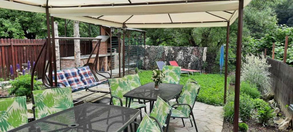 eine Terrasse mit Tischen und Stühlen unter einem Sonnenschirm in der Unterkunft Casa Crissio in Sinaia
