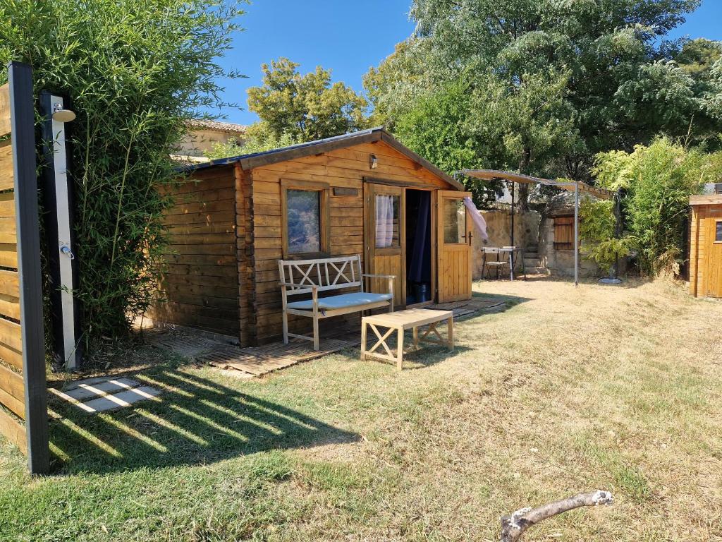 a small wooden cabin with a bench in the yard at Locations insolites "vie en plein air" cabane et tipi Bastide Bellugue maison d'hôtes reseau Bienvenue à la ferme à 3 mn de lourmarin in Cadenet