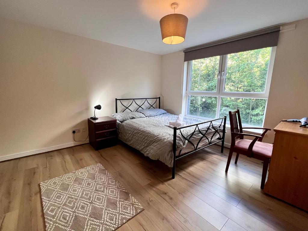 a bedroom with a bed and a table and a window at Lovely 2-Bed Serviced apartment with free parking in Glasgow
