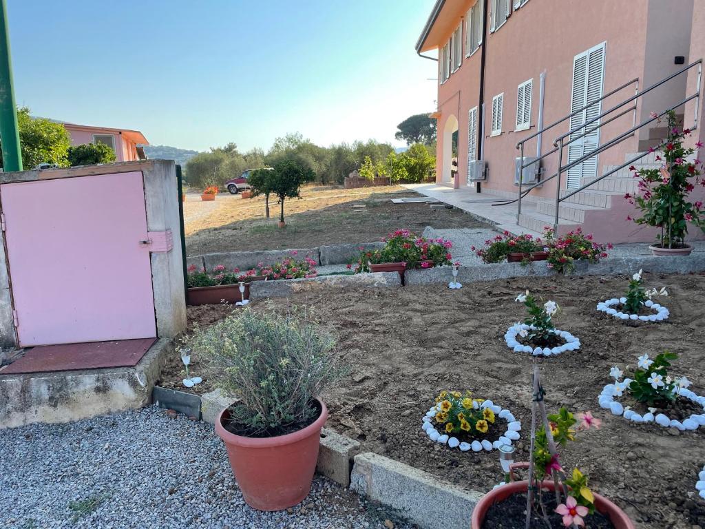 um jardim com vasos de plantas e flores ao lado de um edifício em Il Vecchio Casale em Porto Azzurro