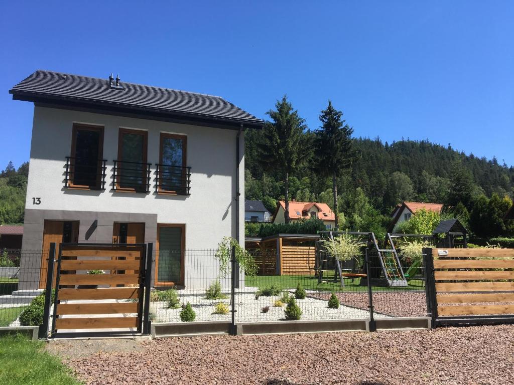 a white house with two wooden gates in front of it at Apartamenty Black&White Lubawka - Domek z ruską banią i sauną in Lubawka