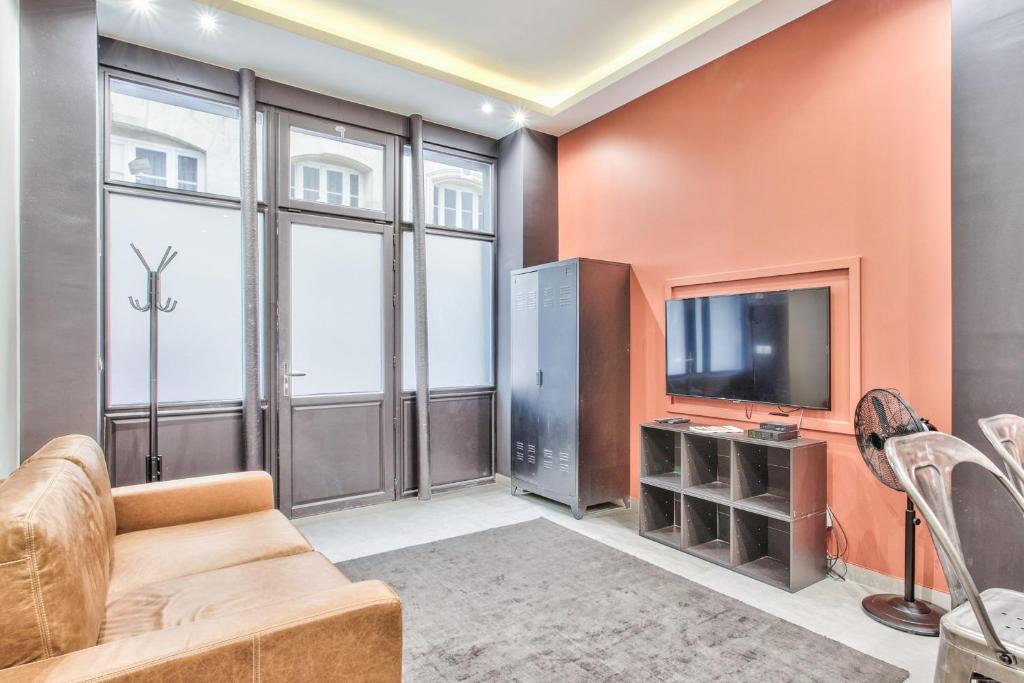 un salon avec un canapé et une télévision dans l'établissement Studio Rambuteau - Welkeys, à Paris