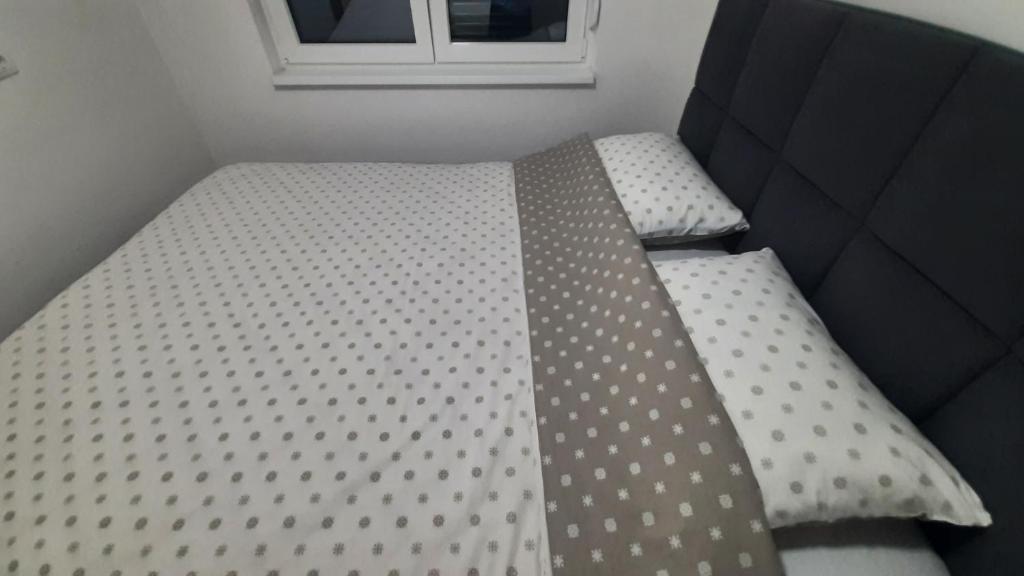 a bed with polka dot sheets in a room at Apartman 222 in Brčko