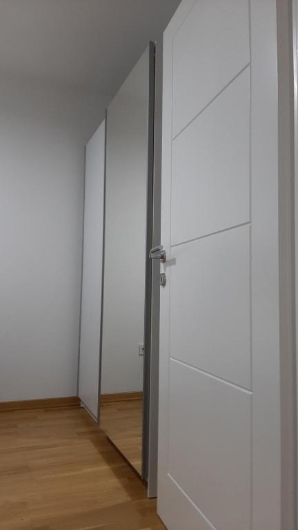 an empty room with white doors and a wooden floor at Apartman 222 in Brčko