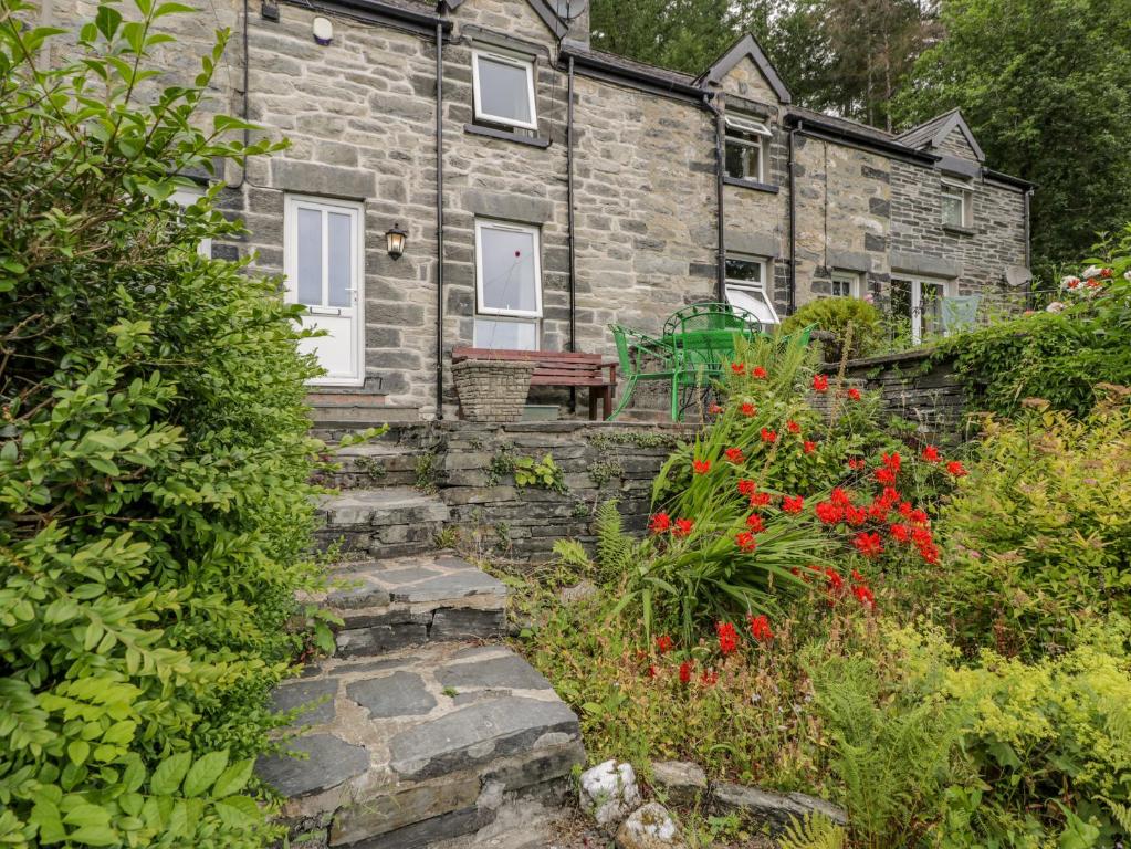 an old stone house with a garden in front of it at Awelfryn in Betws-y-coed