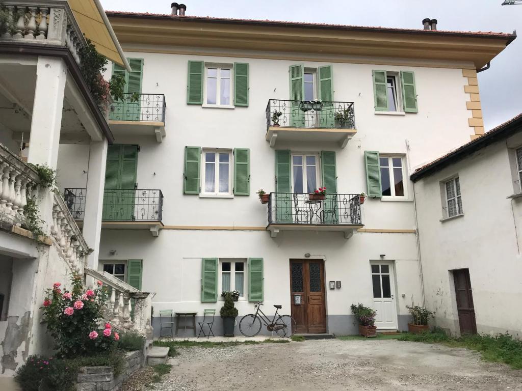 a white house with green shutters and a bike parked in front at Le sou tri in Aosta