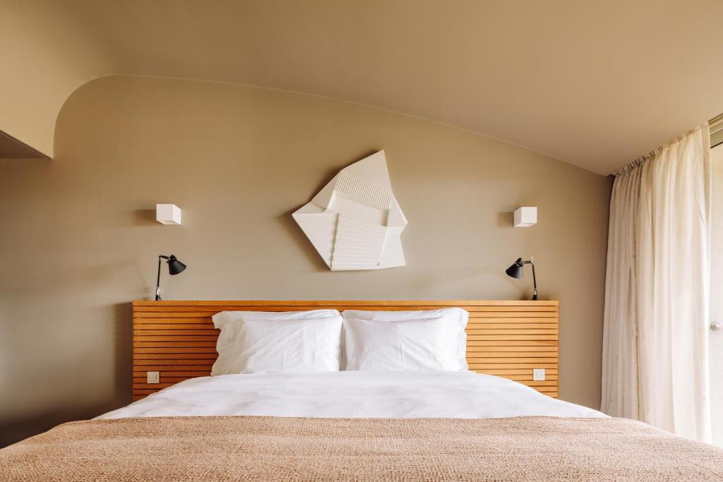 a bedroom with a bed with a wooden headboard at Immerso Hotel, a Member of Design Hotels in Ericeira