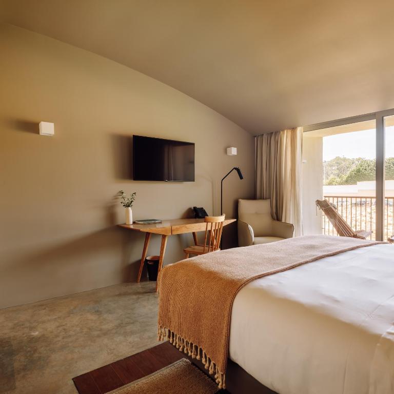 a bedroom with a bed and a desk and a window at Immerso Hotel, a Member of Design Hotels in Ericeira