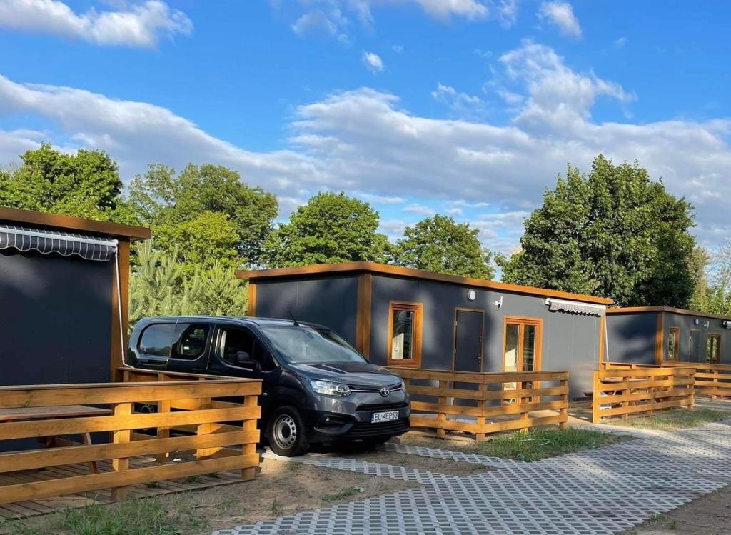 Ein schwarzer Truck parkt vor einem winzigen Haus. in der Unterkunft Zajazd we Młynie - Domki letniskowe in Lubięcin
