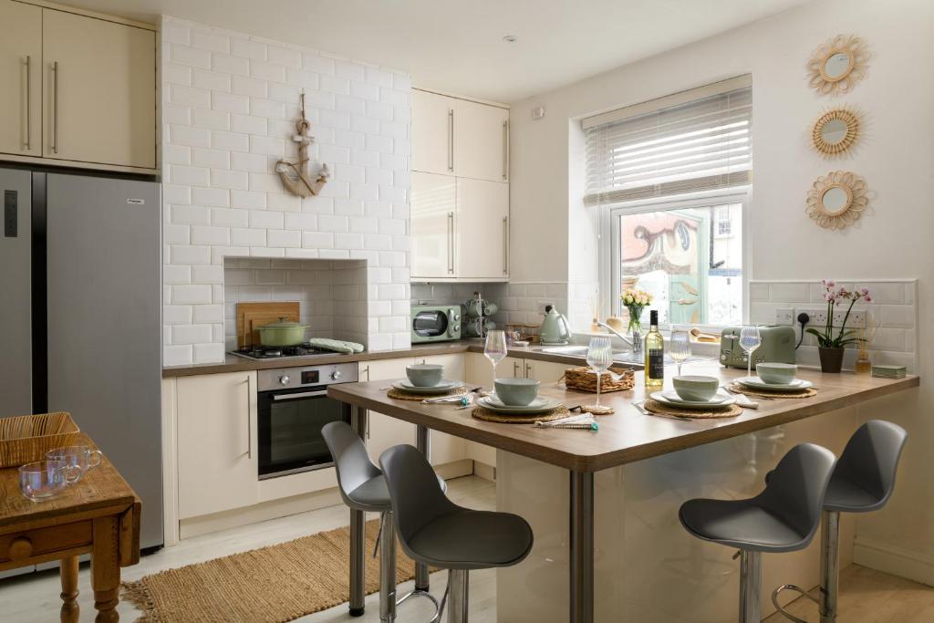 uma cozinha com uma grande ilha com cadeiras em Modern, light and airy townhouse in Llandudno, West Shore em Llandudno
