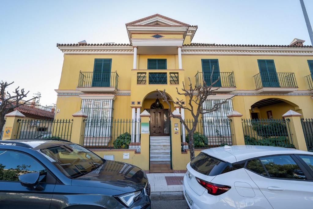 two cars parked in front of a yellow house at VILLA CAPITAN in Sanlúcar de Barrameda