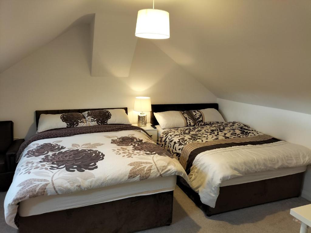 two beds in a attic bedroom with a lamp on a table at NHYL HOMES in Wibsey