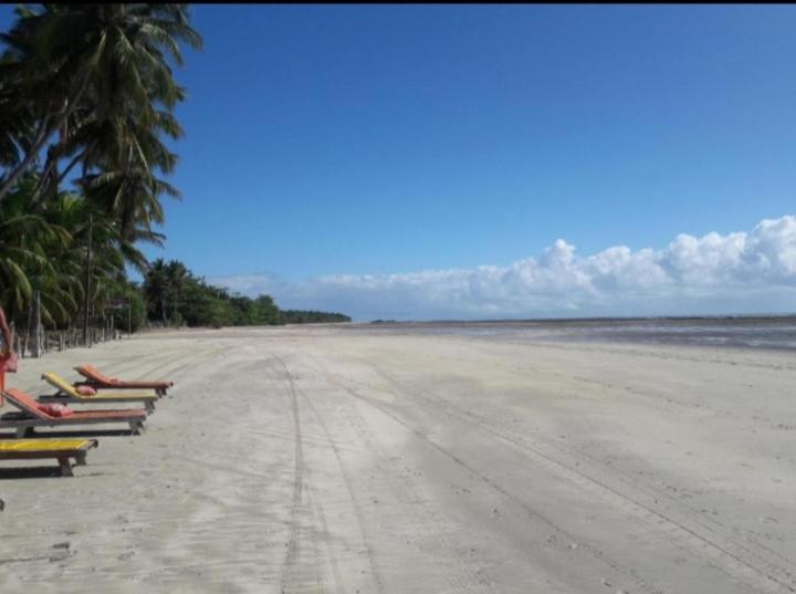 una playa de arena con sillas y palmeras. en Axé Mainha Flats! Quarta Praia!, en Morro de São Paulo