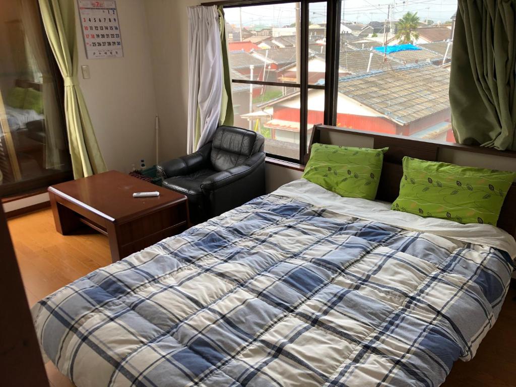 una camera da letto con un letto, una sedia e una finestra di コウノトリの里の宿 a Fukiage