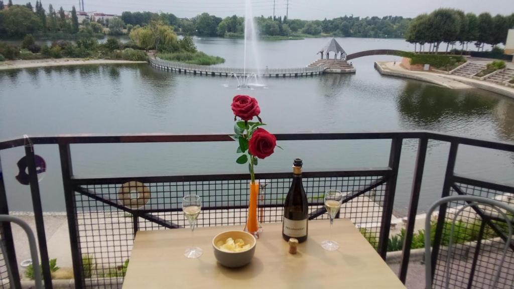 un tavolo con una bottiglia di vino e un fiore sopra di VUE EXCEPTIONNELLE SUR LE LAC a Créteil