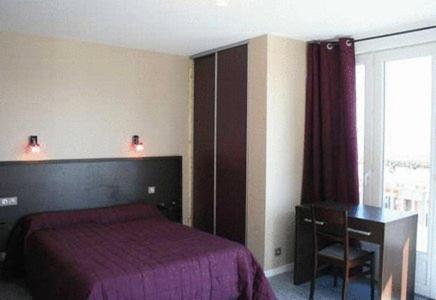 a bedroom with a bed and a desk and a window at Hotel Le Richelieu in Le Tréport