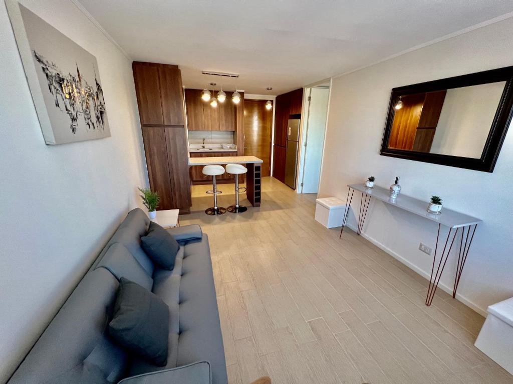 Una sala de estar con un sofá azul y una cocina. en Departamento Central Ejecutivo- Apart Hotel, en Calama