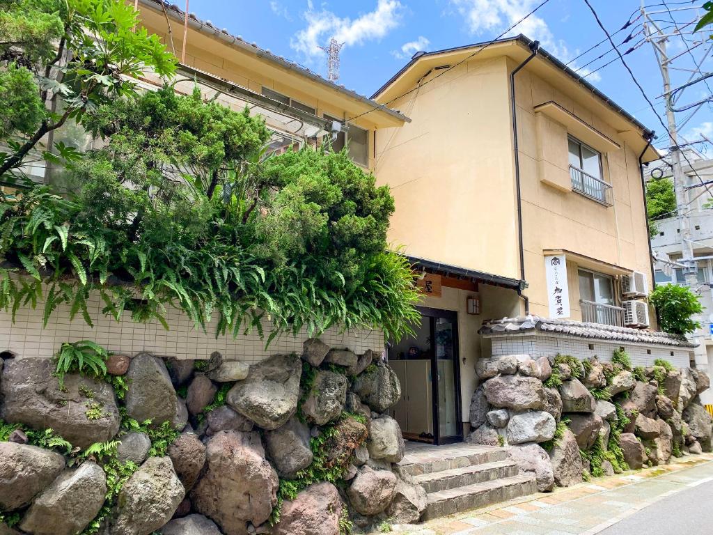 ein Haus mit einer Felswand davor in der Unterkunft Beppu no Oyado Kagaya in Beppu