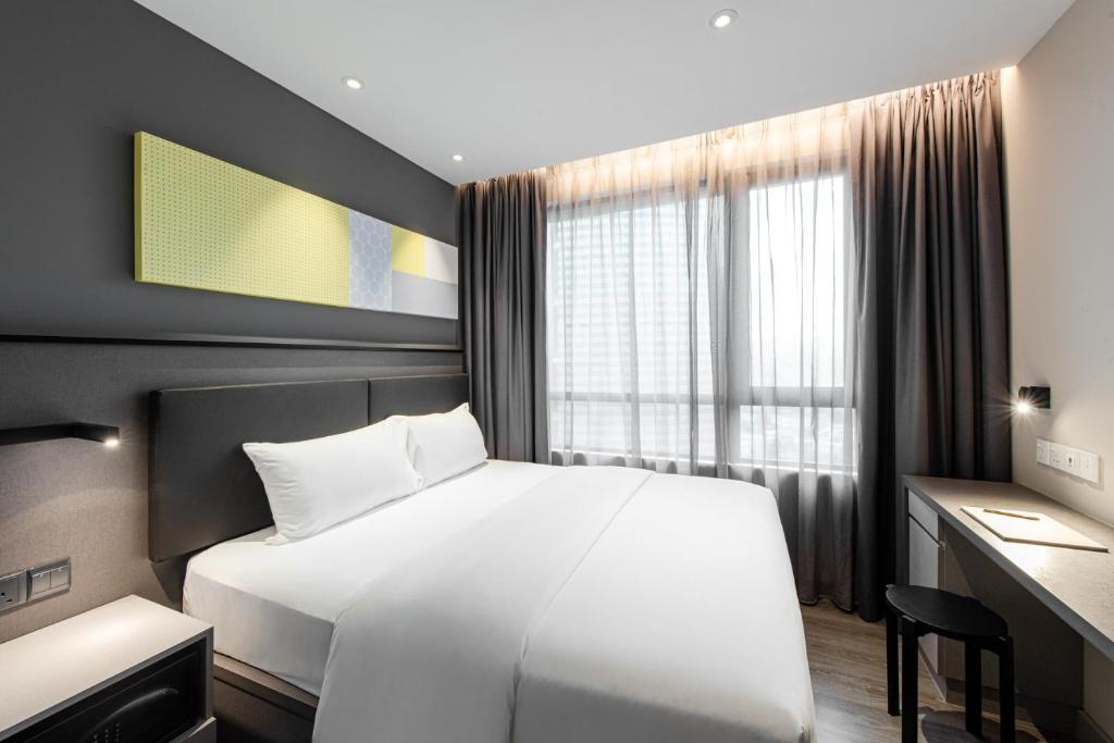 a bedroom with a large white bed and a desk at Komune Living in Kuala Lumpur