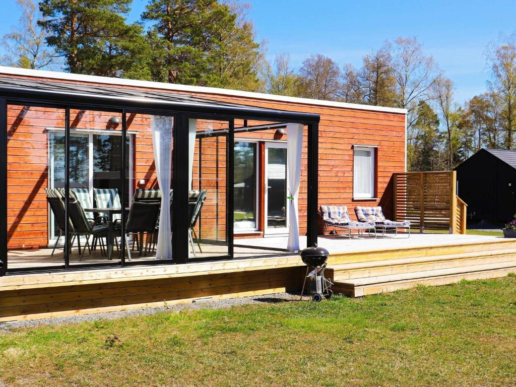 a small house with a deck with a table and chairs at Holiday home SÄFFLE IV in Säffle