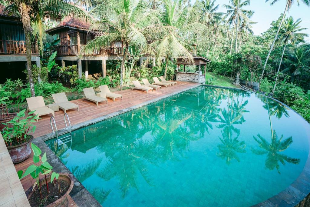 una piscina en un complejo con sillas y árboles en Pertiwi Bisma 1, en Ubud
